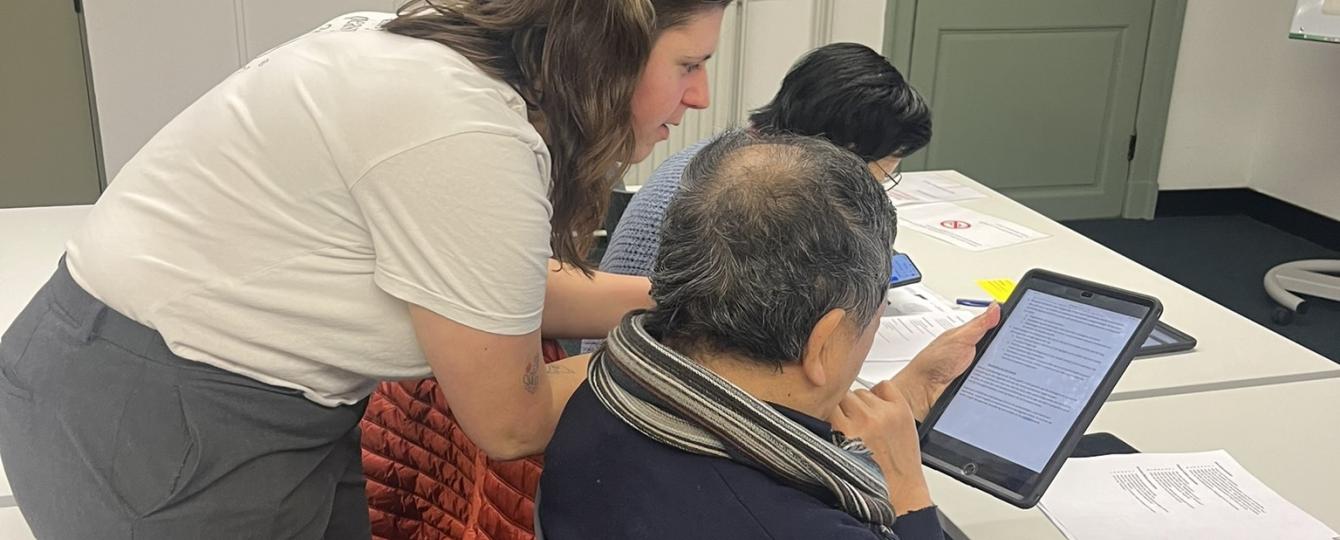 Educatieve medewerker helpt iemand met zijn tablet.