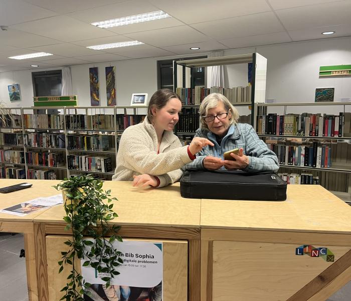 Vrijwilliger helpt oudere persoon met smartphone 