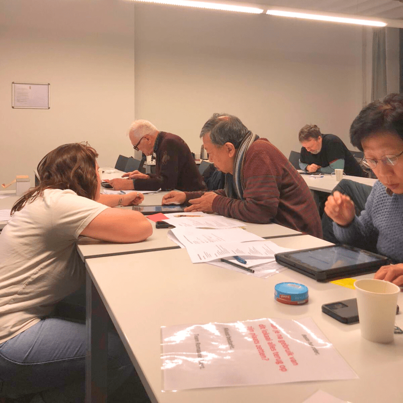 Educatieve medewerker helpt iemand met zijn tablet.